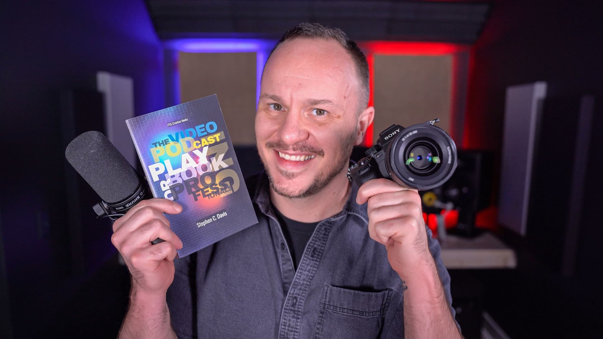 Stephen C. Davis holding The Video Podcasting Playbook for Professionals, a microphone, and a camera.